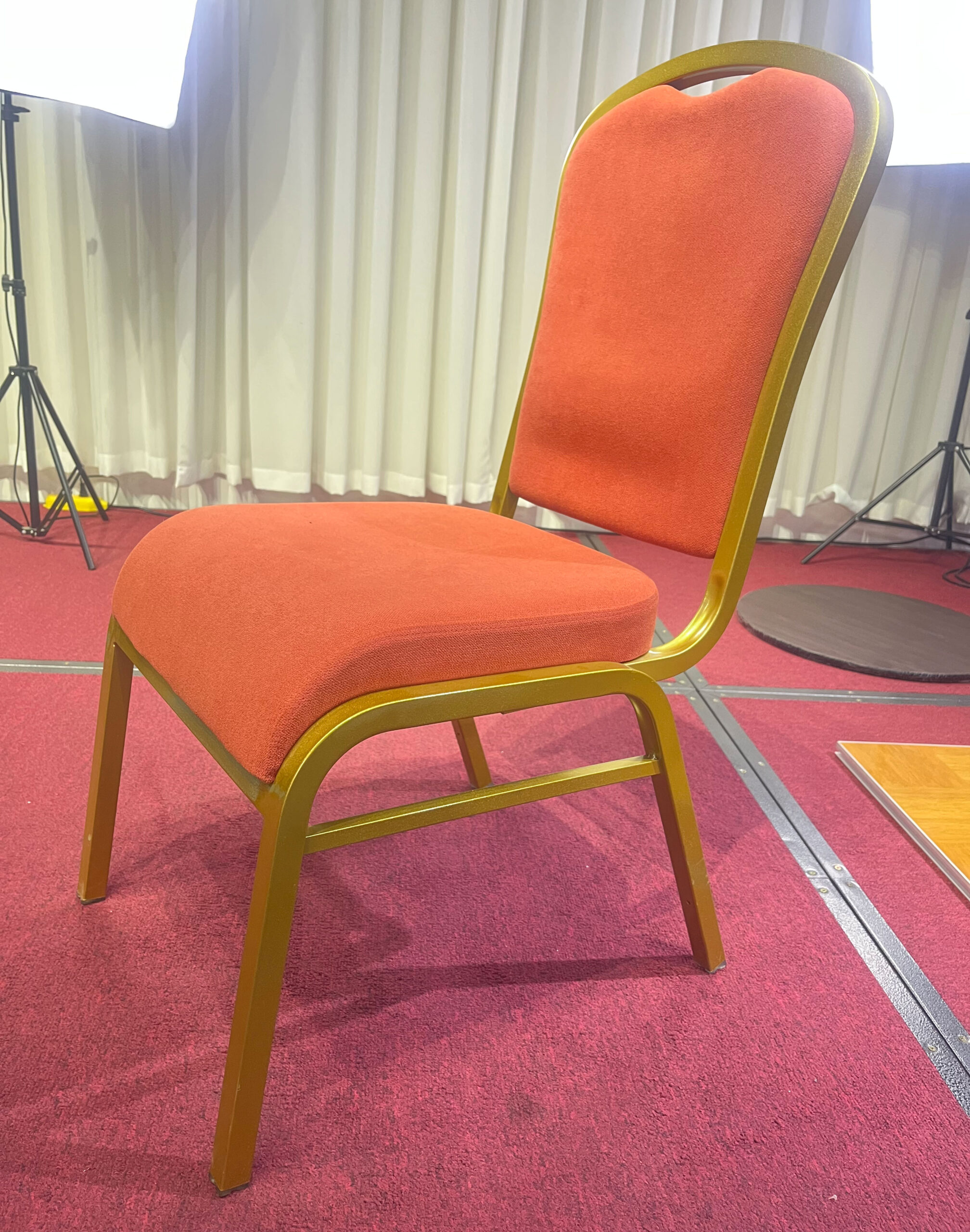 Side view of Auralis Series aluminum banquet chair with orange-red fabric upholstery