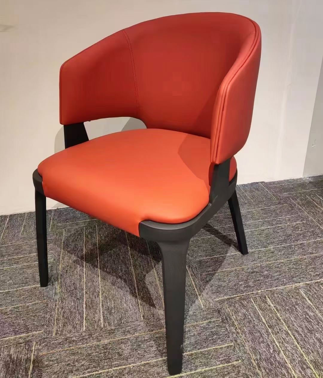 Red upholstered dining chair with curved backrest and black metal legs, angled front view from the Aurelia Series