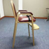 Side angle of maroon upholstered hotel baby high chair with armrests, footrest, and safety belt