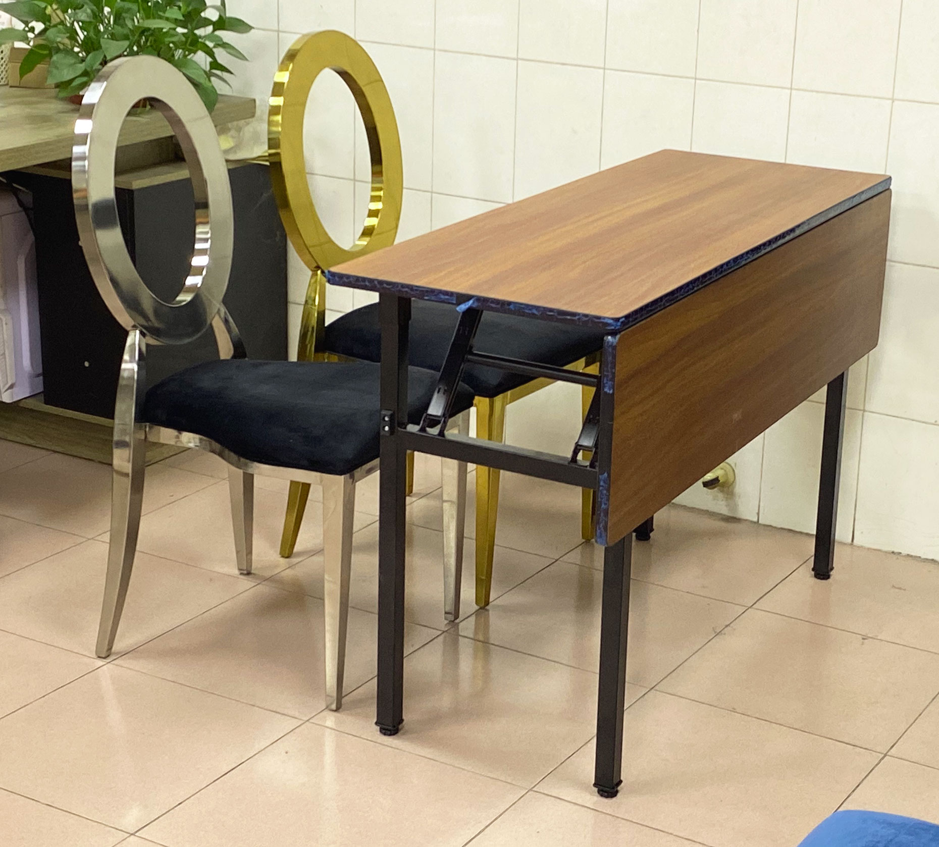 Side angle view of IBM training table with foldable MDF modesty panel and metal frame, placed beside modern event chairs