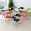 Folding student chairs in multiple colors with writing tablets and under-seat book racks in a classroom setting