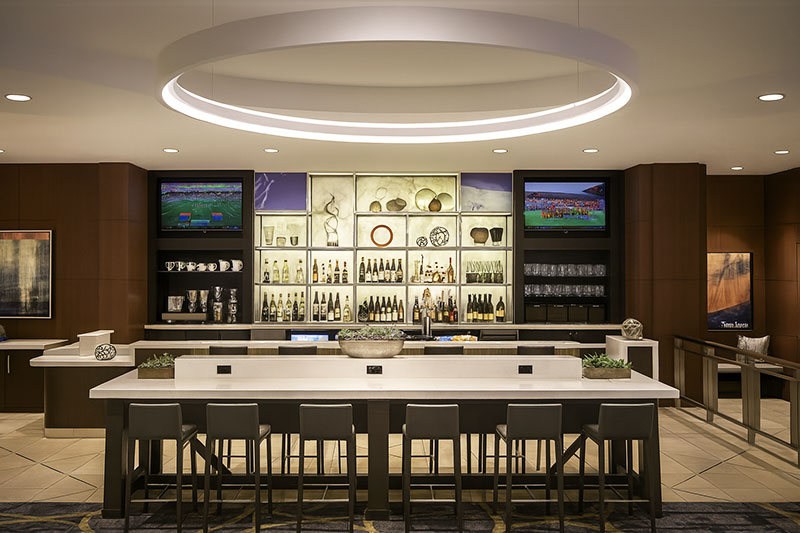 Modern-Hotel-Bar-Setup-with-High-Stools-and-Backlit-Liquor-Display