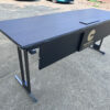 Custom training table side view showing brushed black frame, foldable modesty panel, power socket, USB charging port, and 25mm scratch-resistant surface
