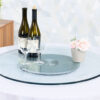 Round tempered glass Lazy Susan turntable with frosted center base, wine glasses, wine bottles, and flower pot on banquet table