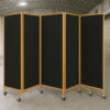 Black acoustic banquet partition with golden frame and caster wheels, movable folding room divider for hotels, events, and conference halls.