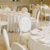 Hotel banquet hall with white Louis-style dining chairs and round tables set for events