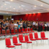 Crowd seated on red stacking banquet chairs at a large indoor conference in Bandung