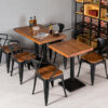 Commercial restaurant dining setup featuring wood-top tables, black metal bases and industrial Tolix armchairs for cafes, bistros, restaurants and hospitality dining spaces.