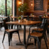 Commercial Tolix dining chairs with arms and natural wood seats used in a modern industrial restaurant and cafe interior setting.