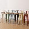 Distressed industrial low-back Tolix stools with solid wood seats in vintage white, mint green, light blue, black, yellow and red finishes for restaurant, cafe and hospitality seating.