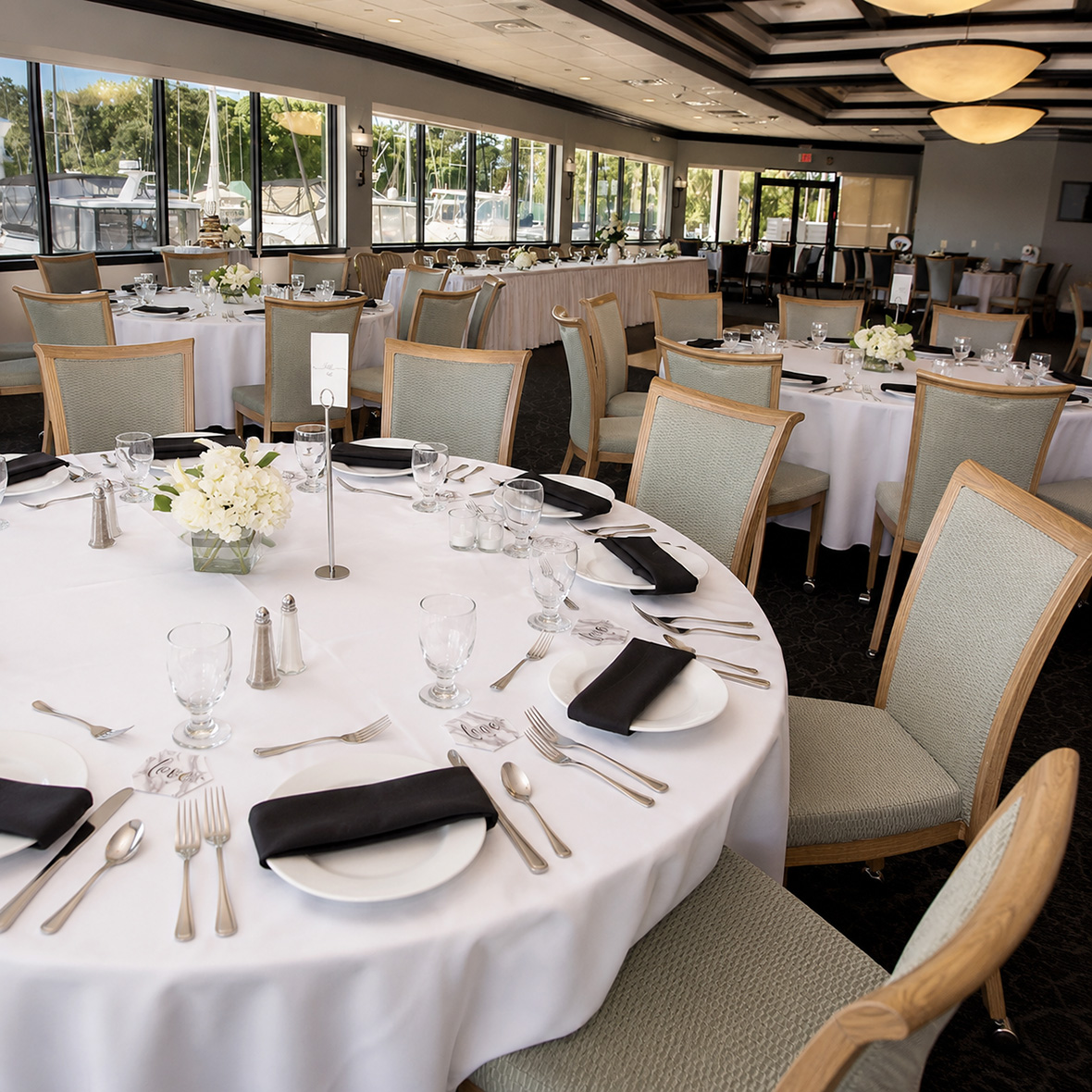 Curved Back Aluminum Dining Chairs with light oak wood grain finish installed in a commercial hotel and restaurant dining project with round banquet tables.