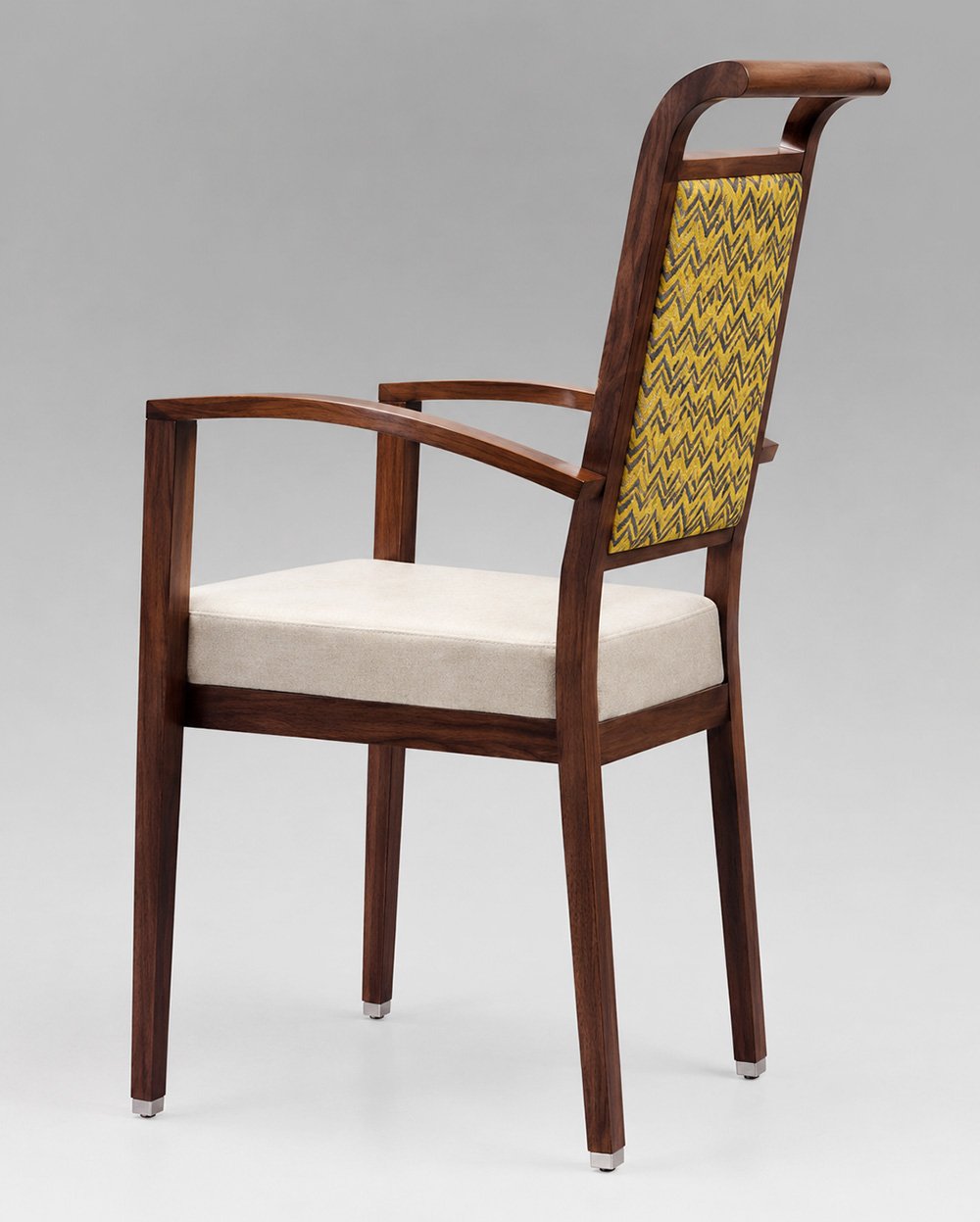 Rear angle view of Harbor Arm aluminum dining chair with front casters, wood grain finish, upholstered seat and patterned backrest for hospitality and senior living spaces.