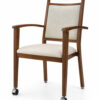 Front three-quarter view of Harbor Arm aluminum dining chair with front casters, wood grain finish, upholstered seat and back for hospitality and senior living dining spaces.